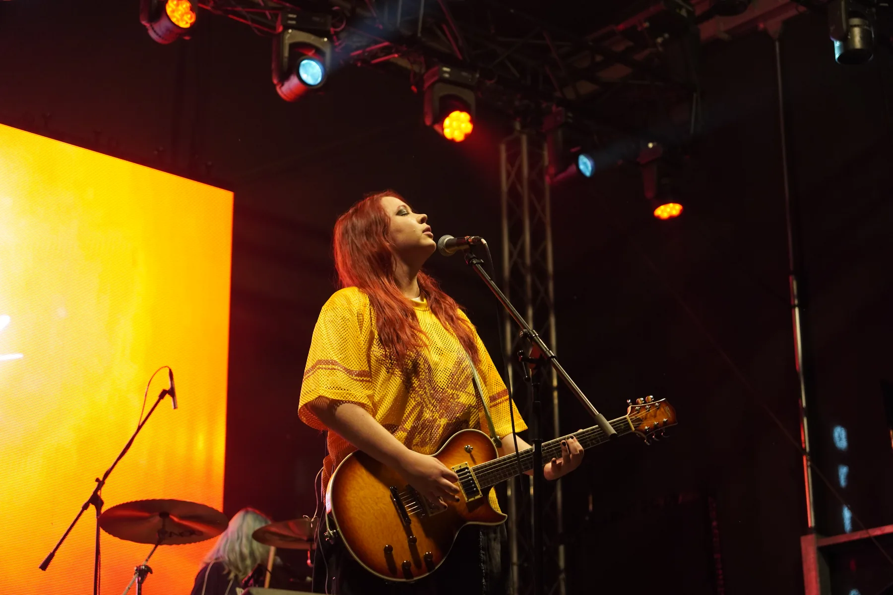 Guitarist singing under stage lights